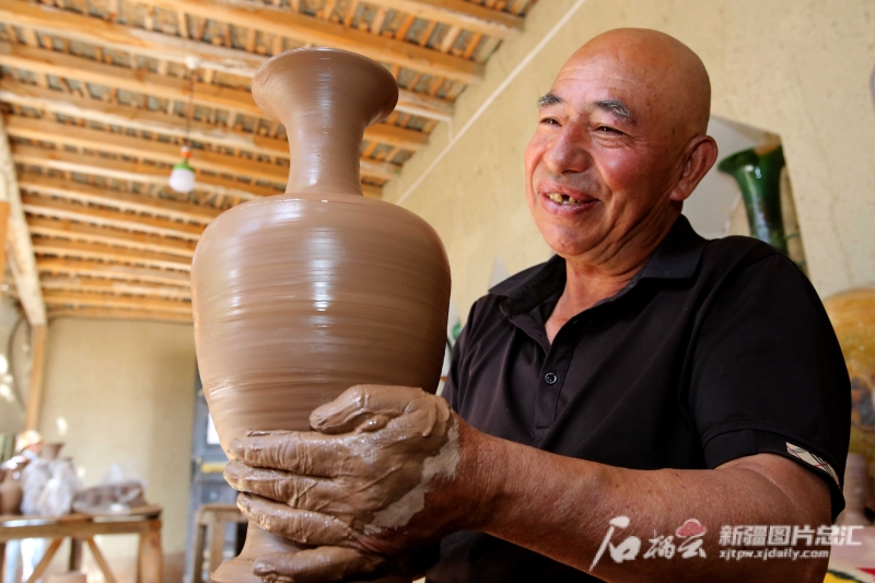 6月19日，英吉沙縣芒辛鎮(zhèn)恰克日庫依村土陶非遺傳承人阿卜杜熱合曼·麥麥提敏在欣賞剛制作的土陶作品。石榴云/新疆日報(bào)記者 蔡增樂 攝